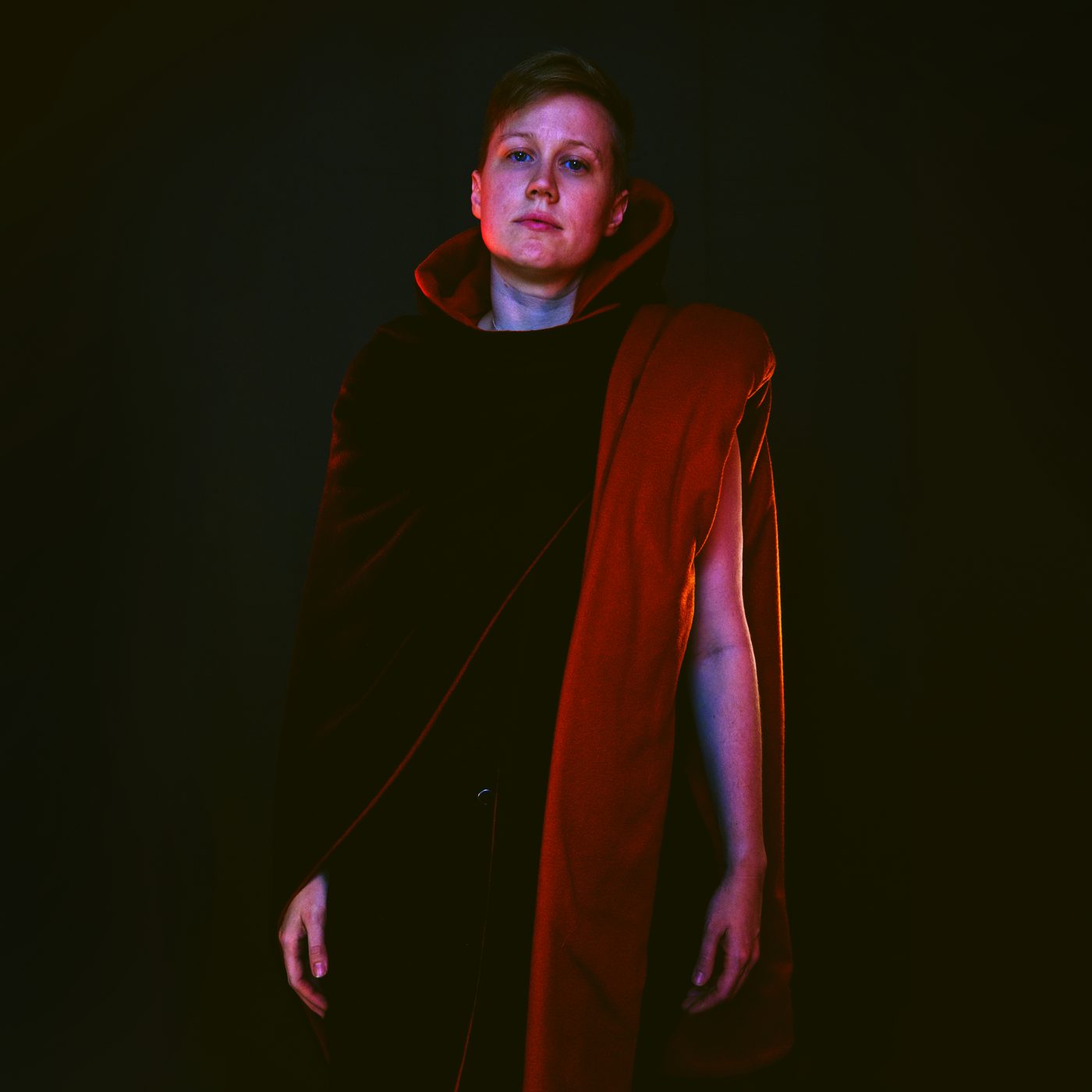 Caspian Turner in a red cloak against a dark background
